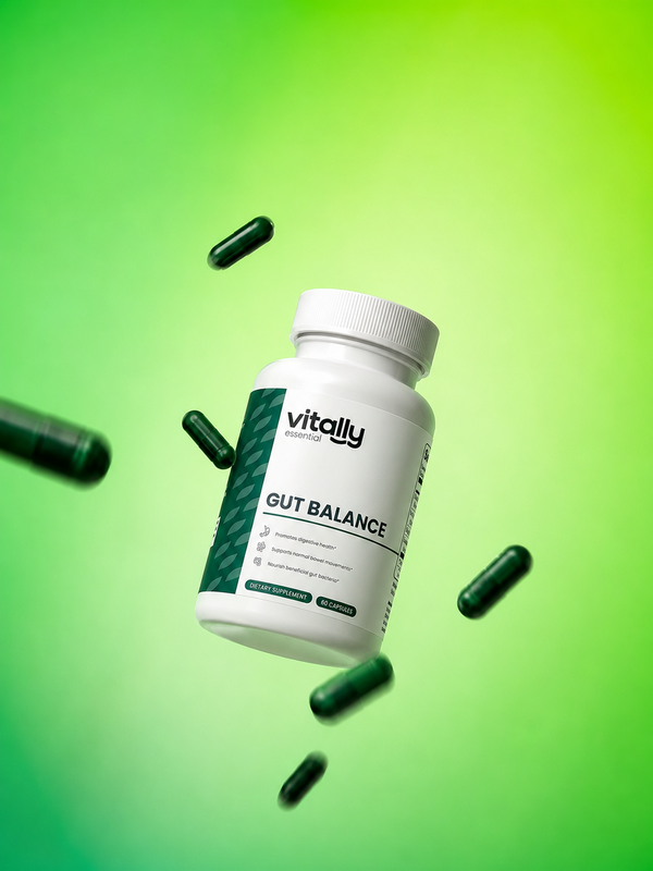 A white supplement bottle labeled 'Vitally Essential GUT BALANCE' floating against a bright green gradient background, surrounded by scattered dark green capsules.