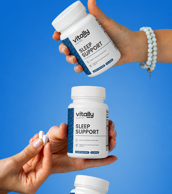 Two hands holding white supplement bottles labeled 'Vitally Essential Sleep Support' against a bright blue background, with one bottle shown upside down and the other upright with a capsule held between fingers.